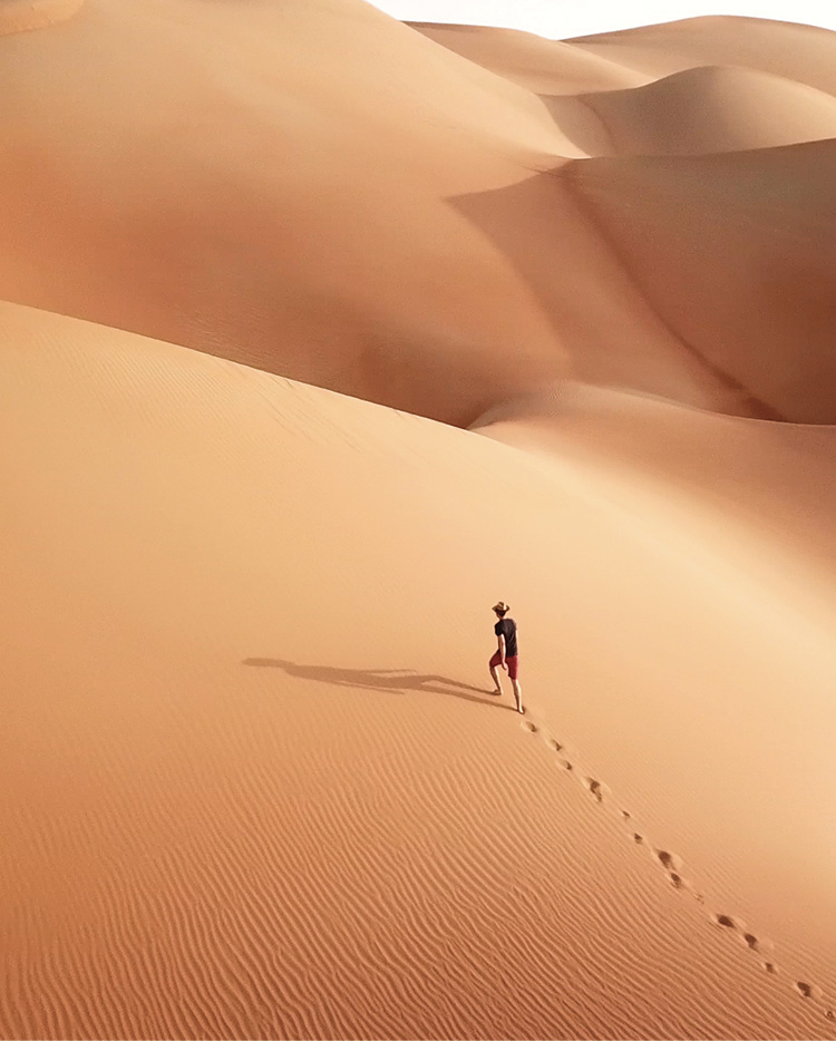 Un uomo percorre una duna di sabbia in salita